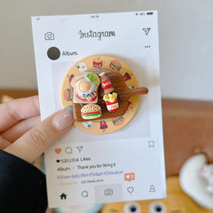 Close-up of the 3D miniature fast food cutting board pop grip on an Instagram-styled display card.