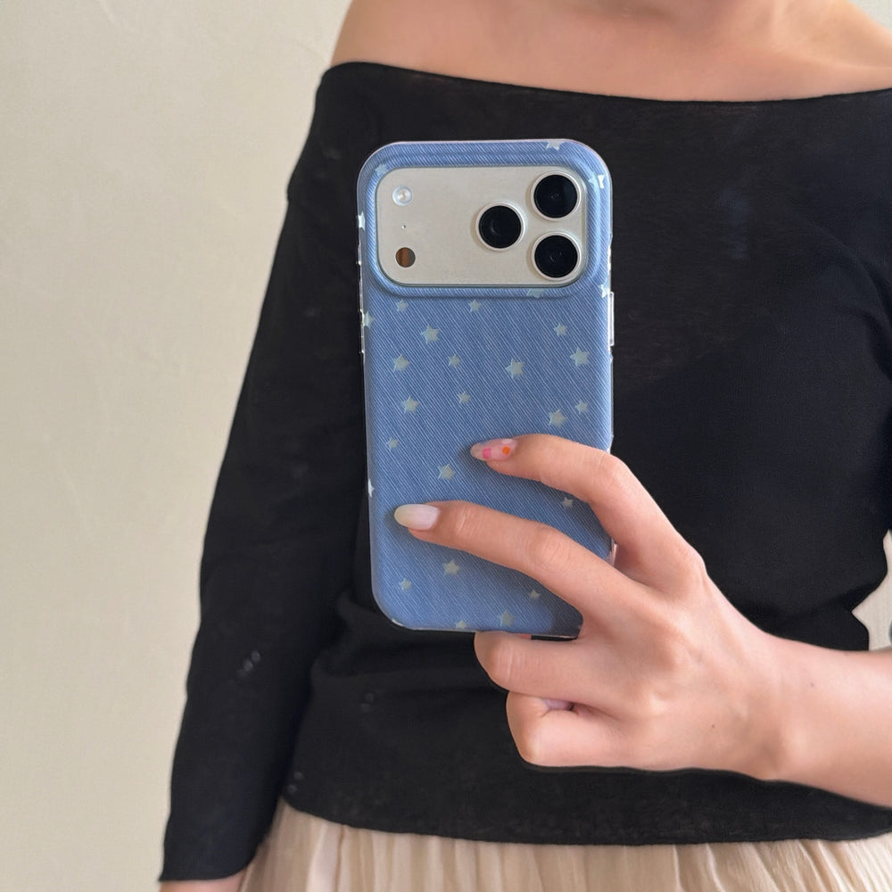 A woman taking a mirror selfie holding a blue textured star iPhone case with the phone's camera showing.
