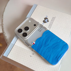 An aesthetic clear phone cover with blue layered wave graphics placed on a white dotted notebook with a dolphin print.