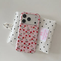An aesthetic cherry phone case resting on a white fabric pouch with black polka dots.