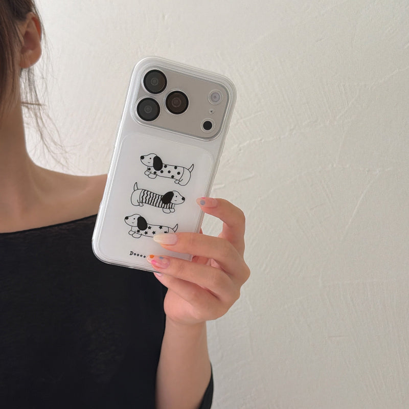 A hand holding a clear aesthetic dachshund pattern iPhone case vertically against a plain wall.