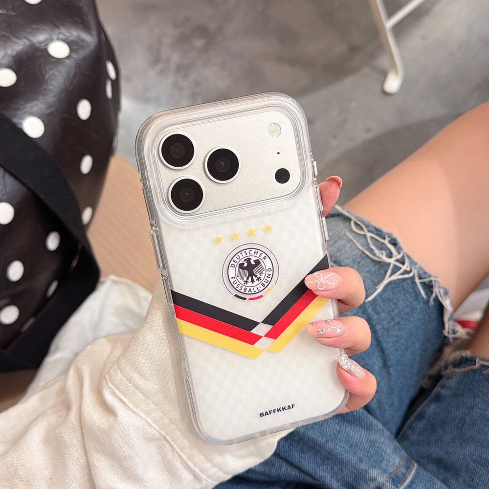 Hand holding a silver Germany team crest mirror phone case with chic nail art and denim jeans background.