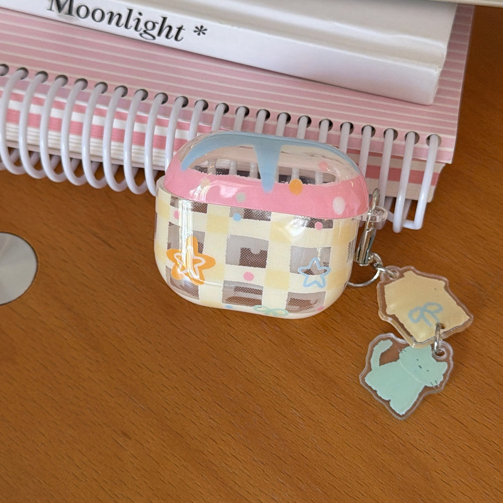 A clear yellow gingham AirPods case resting on a wooden surface under a pink spiral notebook.
