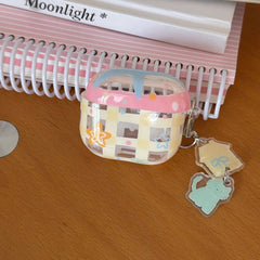 A clear yellow gingham AirPods case resting on a wooden surface under a pink spiral notebook.