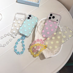 Flatlay of four pastel polka dot iPhone cases with colorful jelly beaded straps in a studio tray.