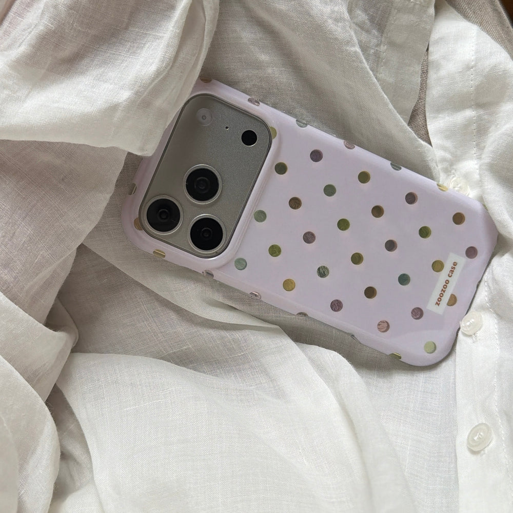 An aesthetic pastel purple polka dot phone case tucked inside a white linen shirt.