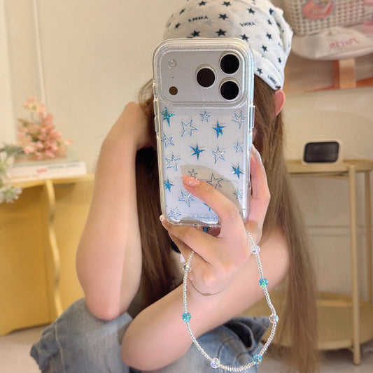 A girl wearing a star bandana holds a silver glitter phone case with teal stars and a crystal charm.
