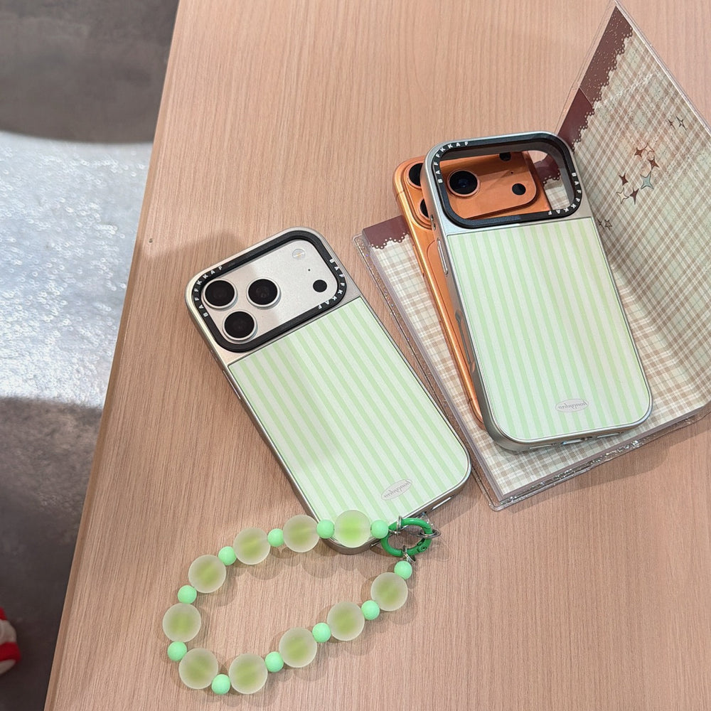 Two aesthetic striped phone cases in silver and orange camera variants placed on a wooden table.