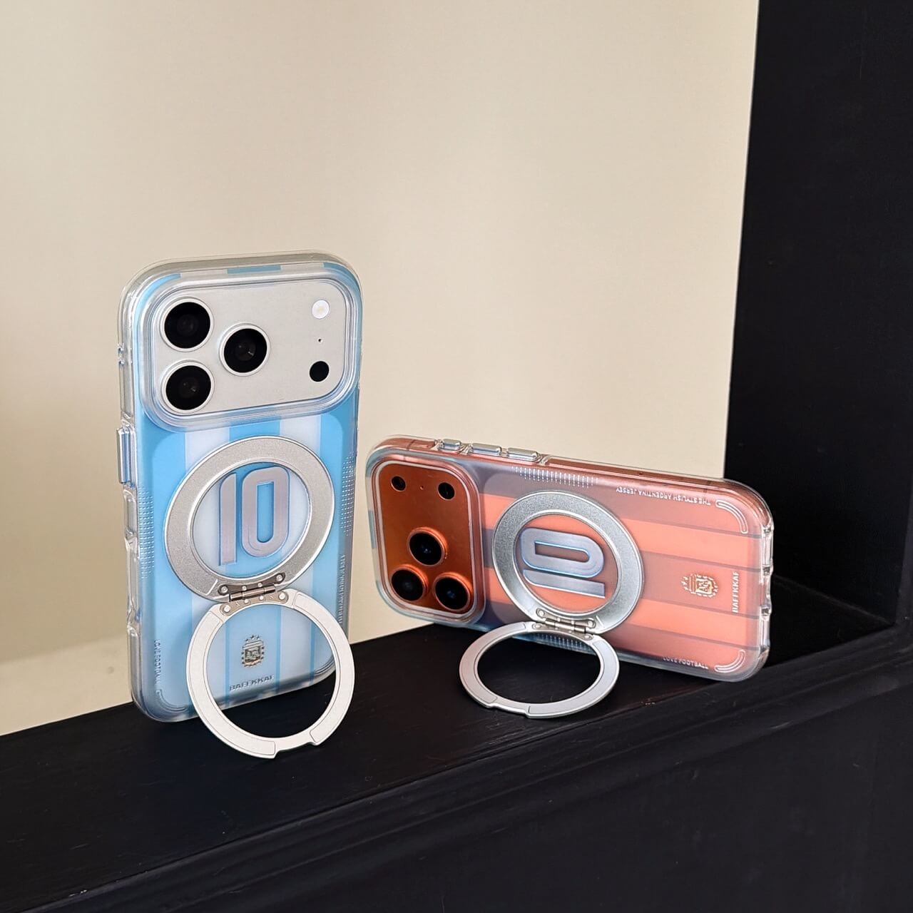 Two Argentina jersey kickstand iPhone cases in blue and pink colors standing on a black ledge.