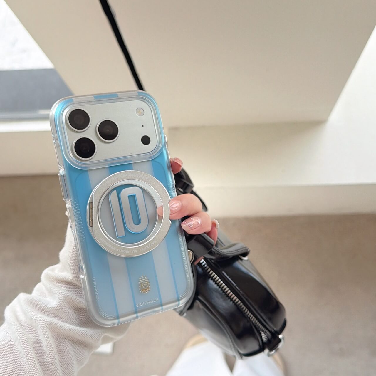 Hand holding an athletic stripe iPhone case showcasing its clear shockproof bumper.