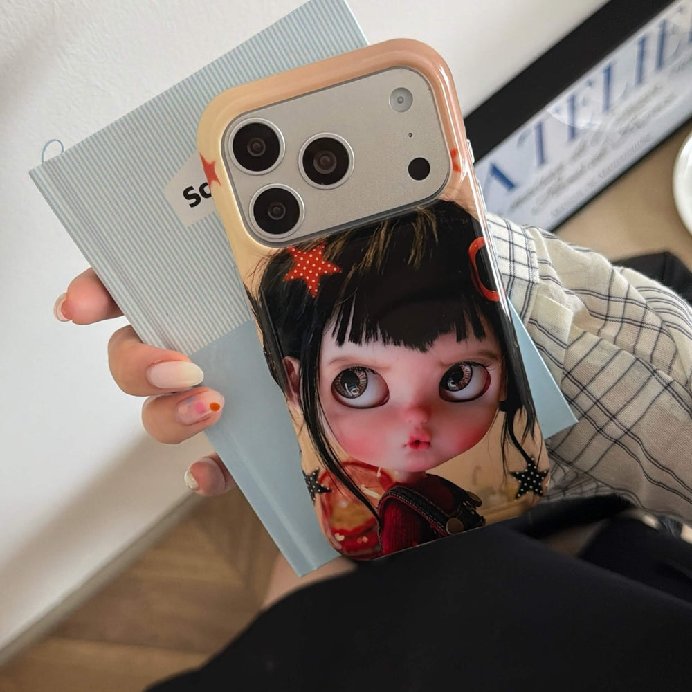 Close-up of a black-haired big-eye doll iPhone case with beige camera frame.