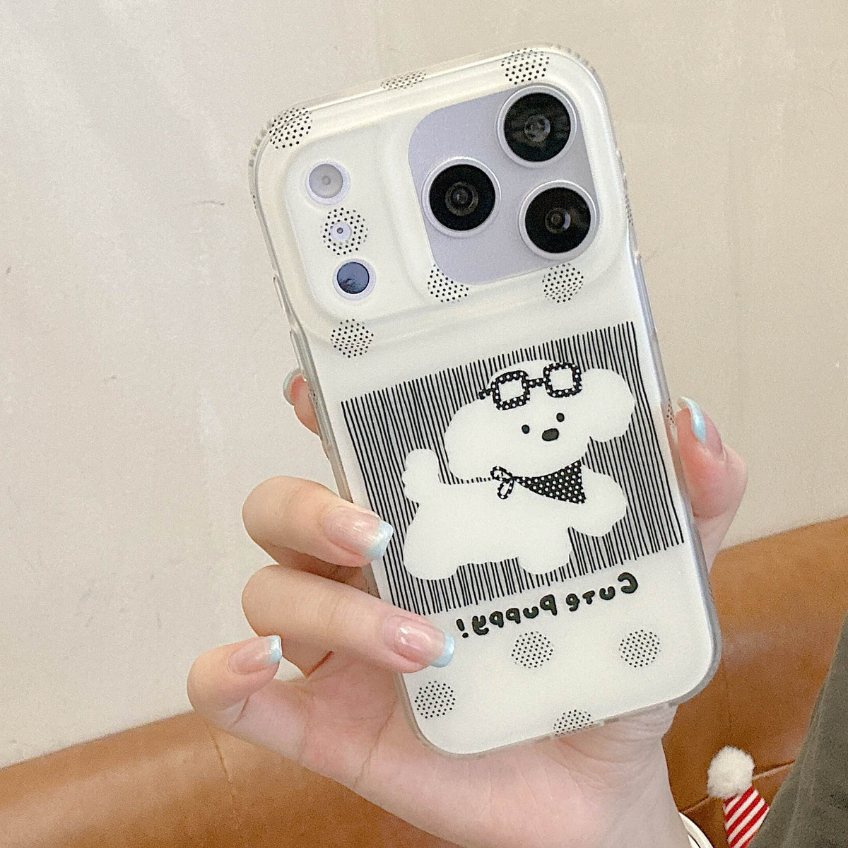 Handheld black polka dot iPhone case with a white puppy graphic.