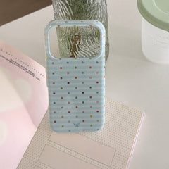 An empty blue stripe phone case shell propped open on a notebook next to a glass vase.