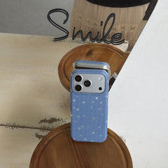 An aesthetic blue textured star phone case leaning against a mirror on a wooden stand.