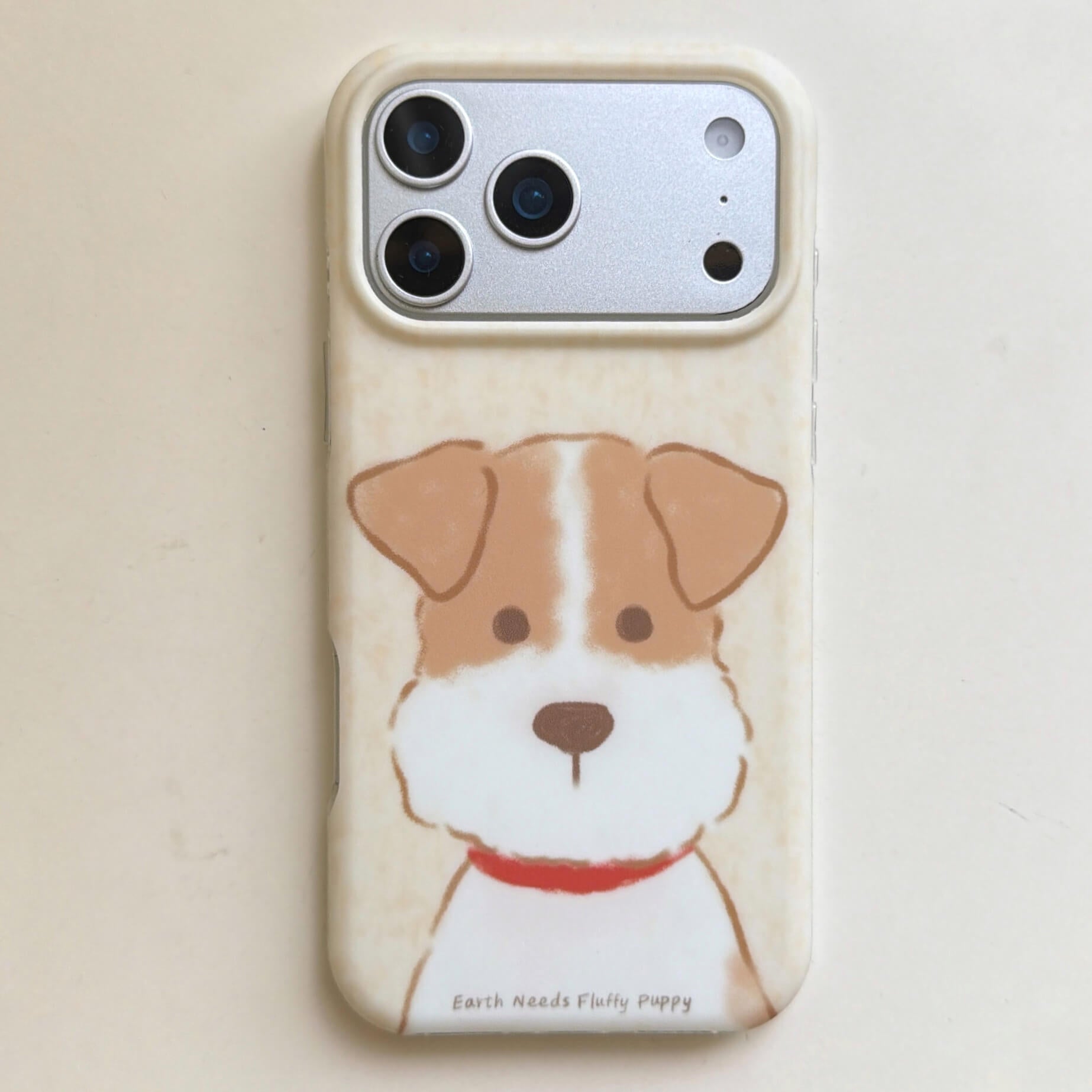 Front product view of a brown and white puppy iPhone case with cream frame.