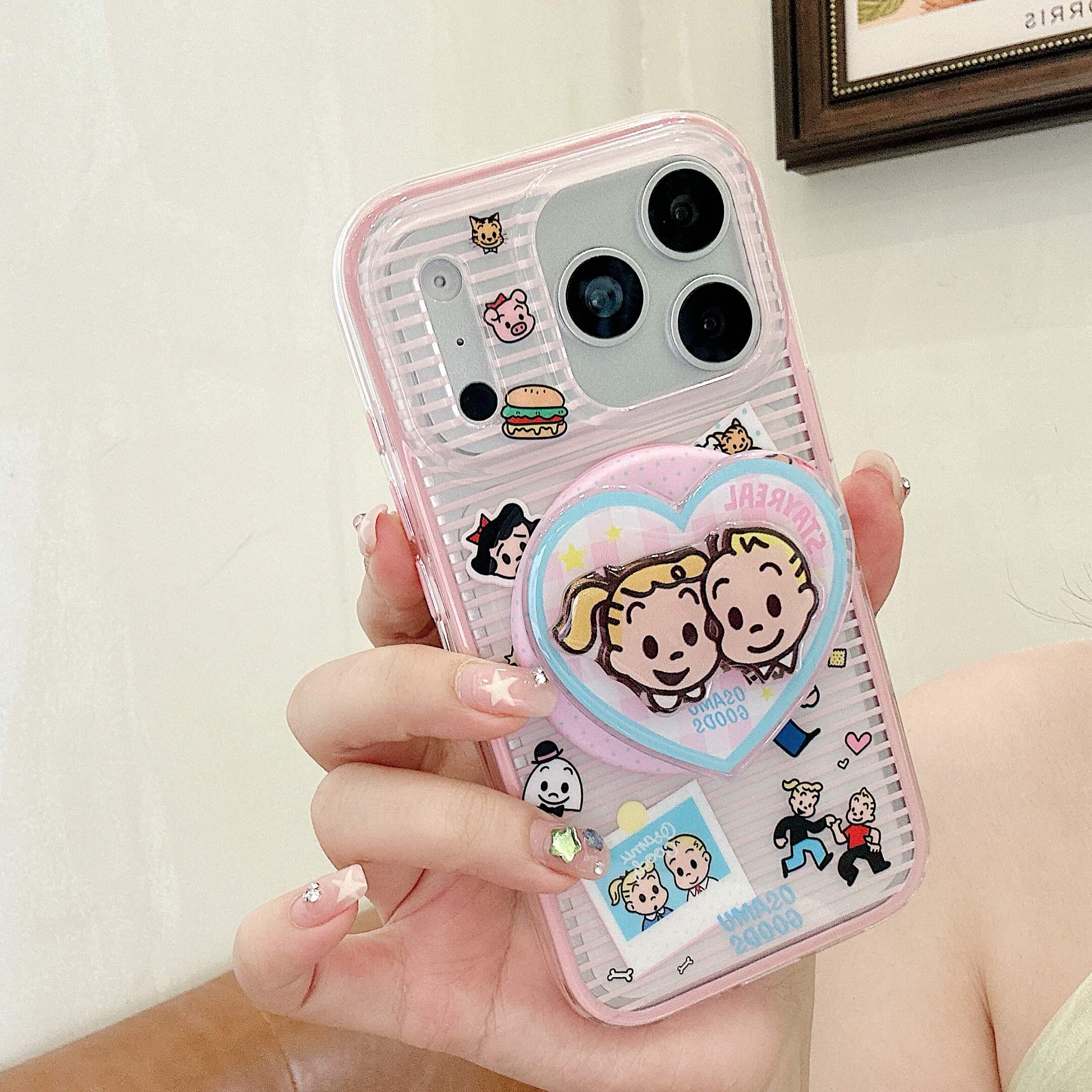 Hand holding a pink clear cartoon couple iPhone case with heart grip.