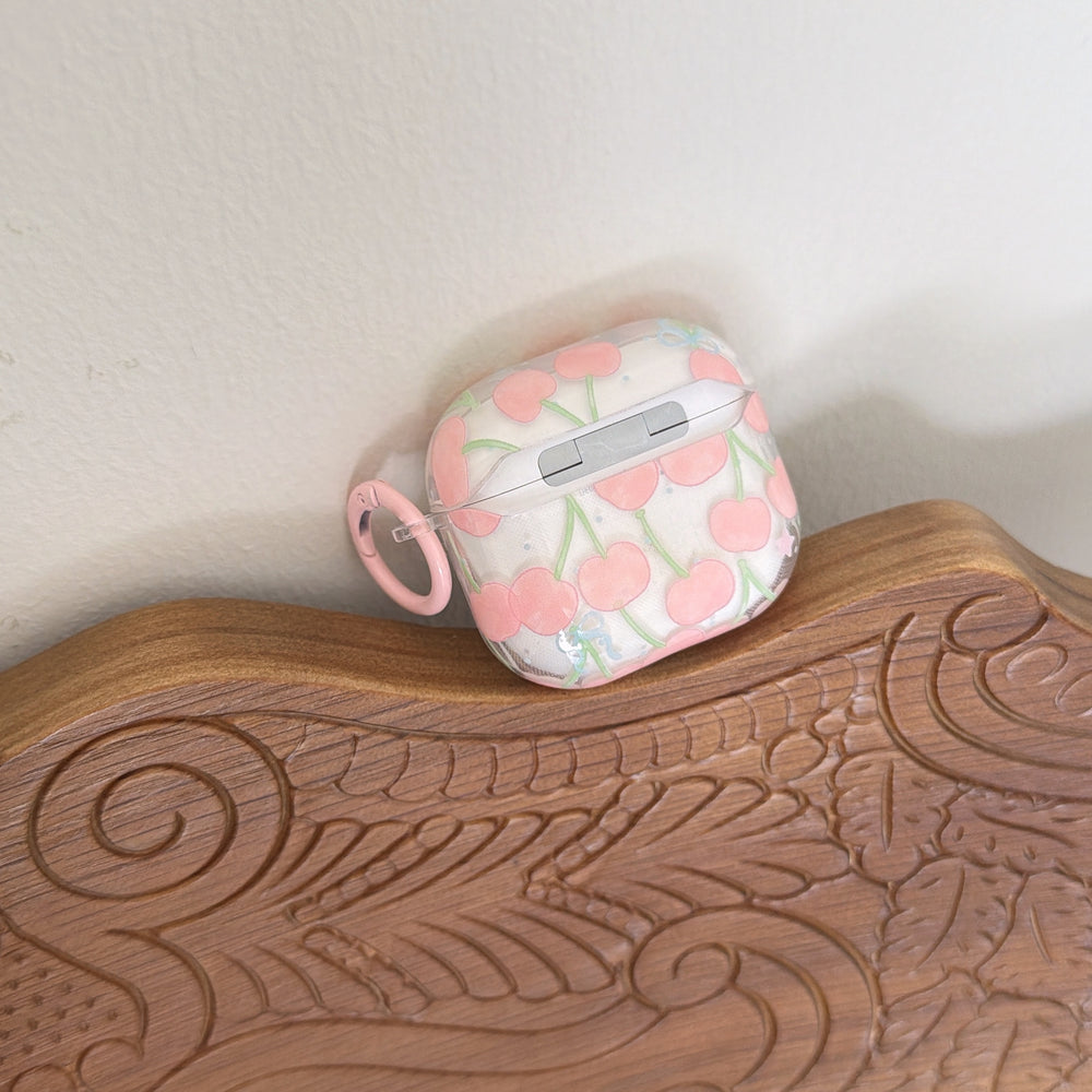 A cherry pattern AirPods case displayed vertically on an elegantly carved dark brown wooden tray.