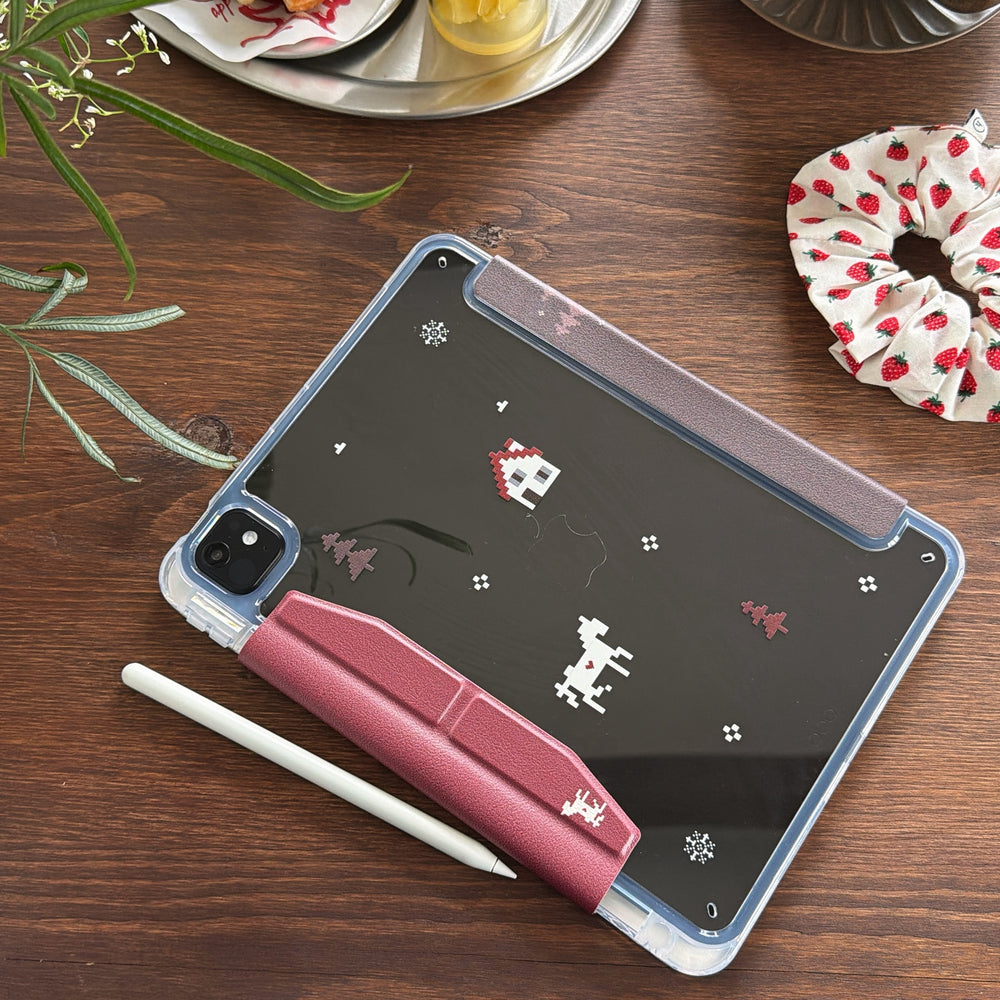 A beautiful flat lay of a clear back iPad case on a dark wood table with a white stylus pen and a strawberry scrunchie nearby.
