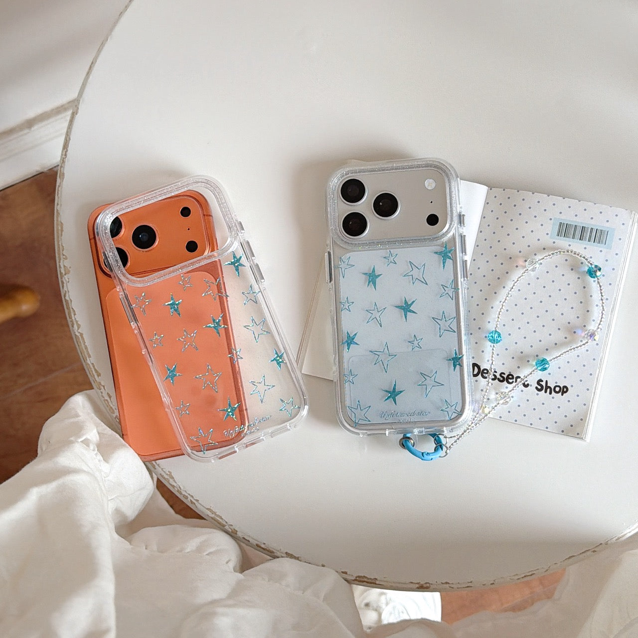 Two clear blue star phone covers displayed next to a polka dot notebook.