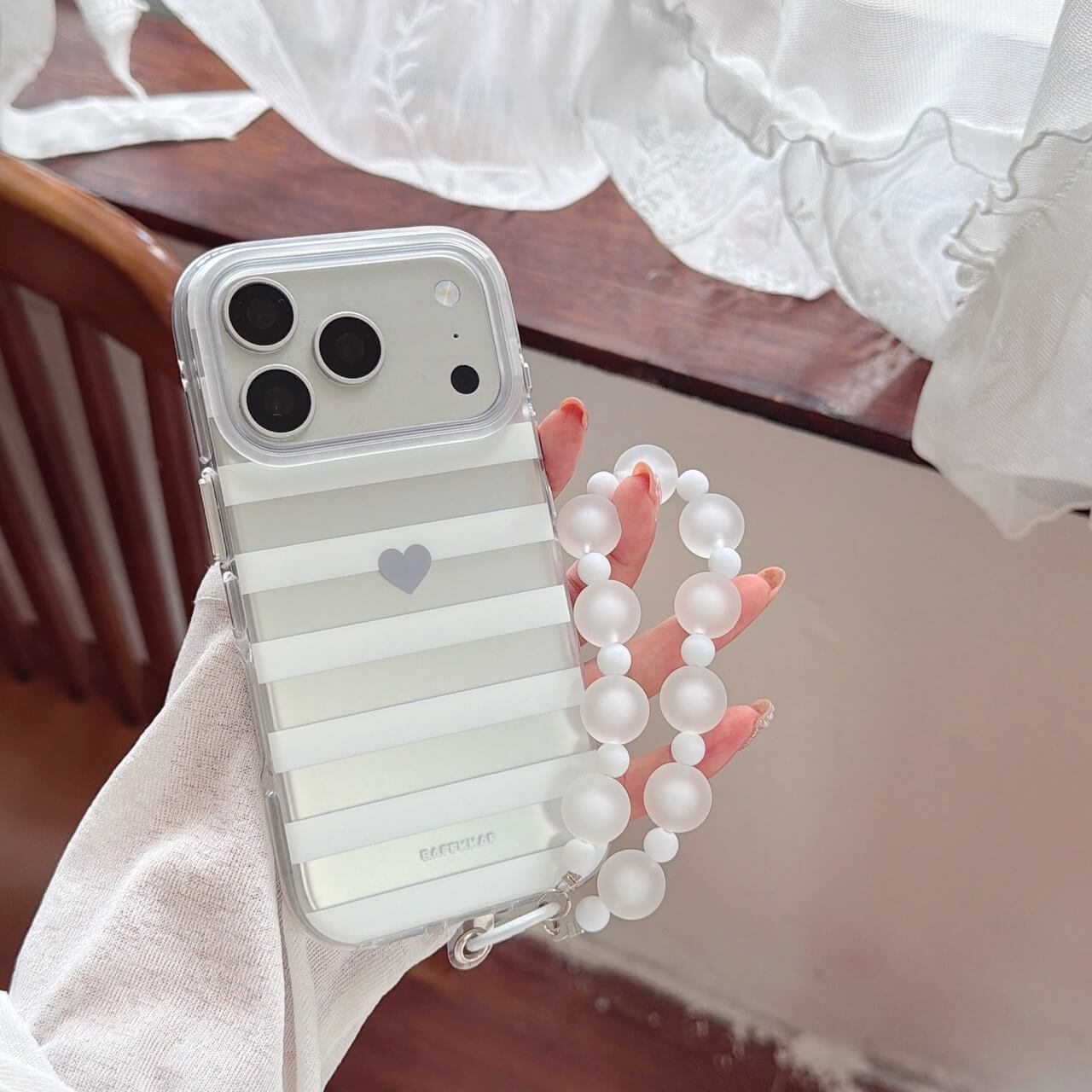 Close-up of clear gray striped iPhone case with detachable bead strap