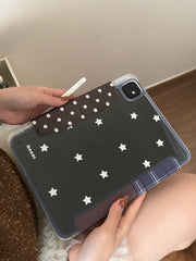 Close-up of a hand holding the clear star back of the iPad case, highlighting the brown polka-dot magnetic pencil clasp securing a white stylus pencil.