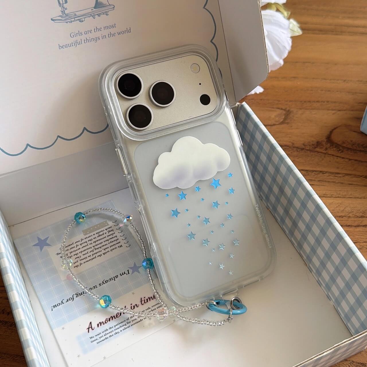 Two variants of the 3D cloud star phone case in silver and orange displayed on a wooden table.
