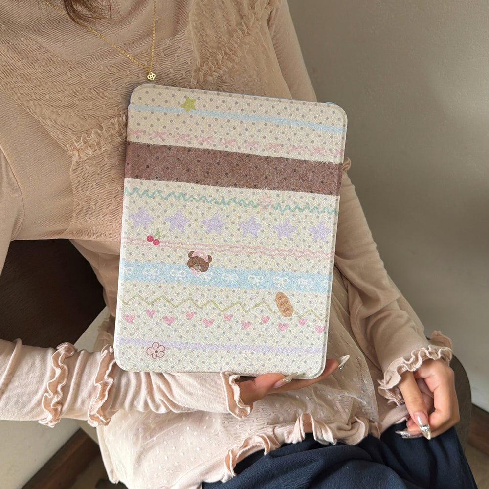 A lifestyle shot of a woman in a ruffled beige coquette-style top holding a closed cute kawaii teddy bear iPad case, emphasizing the trendy aesthetic appeal of the product's design.