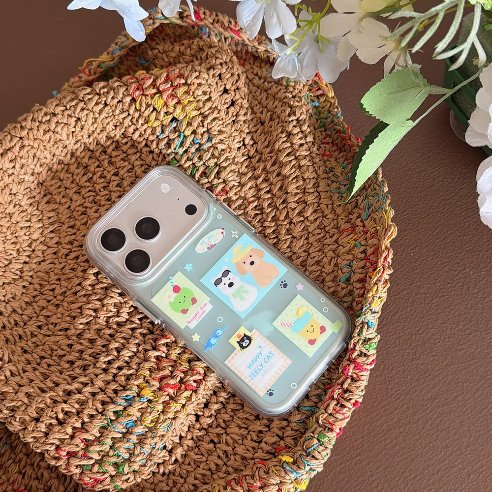 A mint green phone cover featuring puppy and kitten stickers placed inside a woven straw basket with white flowers.