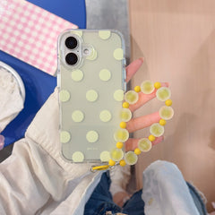A hand showcasing a creamy yellow polka dot iPhone case with a frosted yellow beaded wristlet.