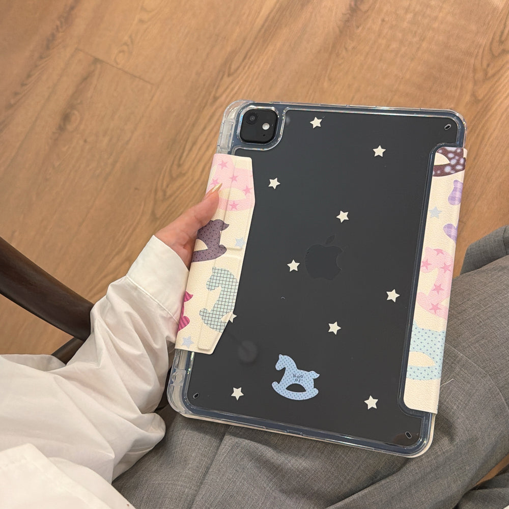 A close-up view showing the clear back panel of a black iPad inside a cute aesthetic origami stand ipad cover, decorated with white stars and a blue horse sticker.
