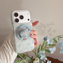 A hand holding a clear holographic flower phone case featuring a built-in cute blue floral phone socket.