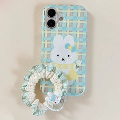 A pastel blue and yellow gingham plaid phone case featuring a white cartoon bunny with a green lace scrunchie strap.