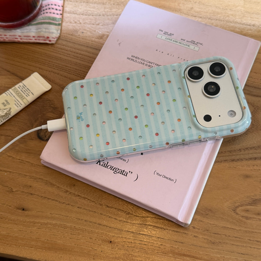 A cute blue striped phone case connected to a charging cable while resting on a pink book.
