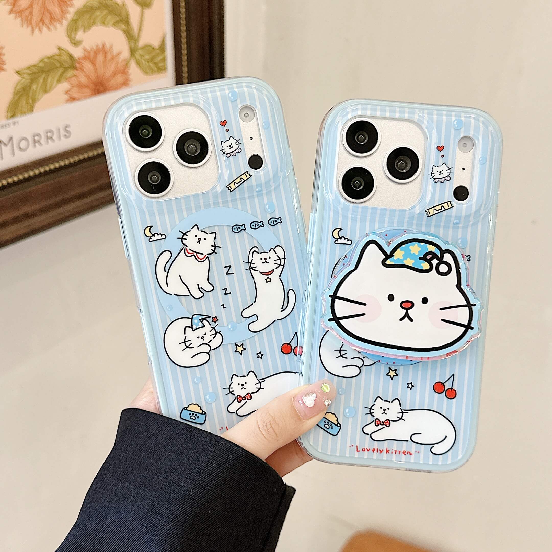 Handheld clear blue iPhone case with white cartoon cats.