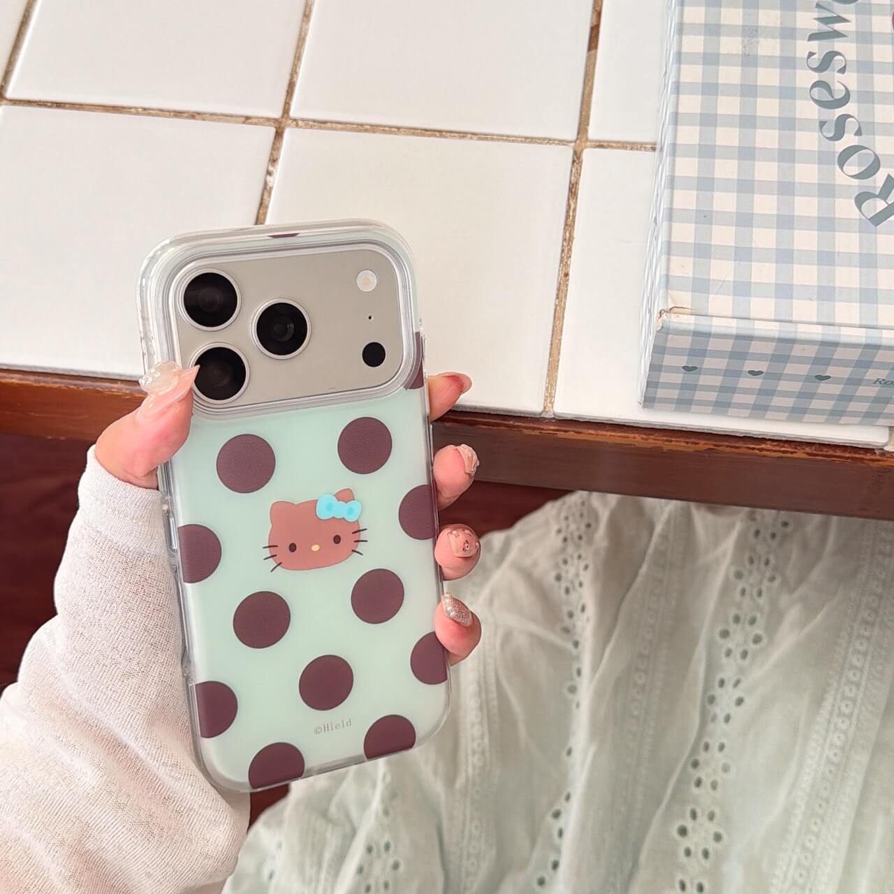 Hand holding mint polka dot clear iPhone case with cute kitty face