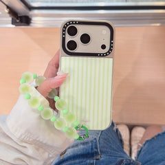 Handheld view of a cute Korean style green stripe phone shell with denim shorts in the background.