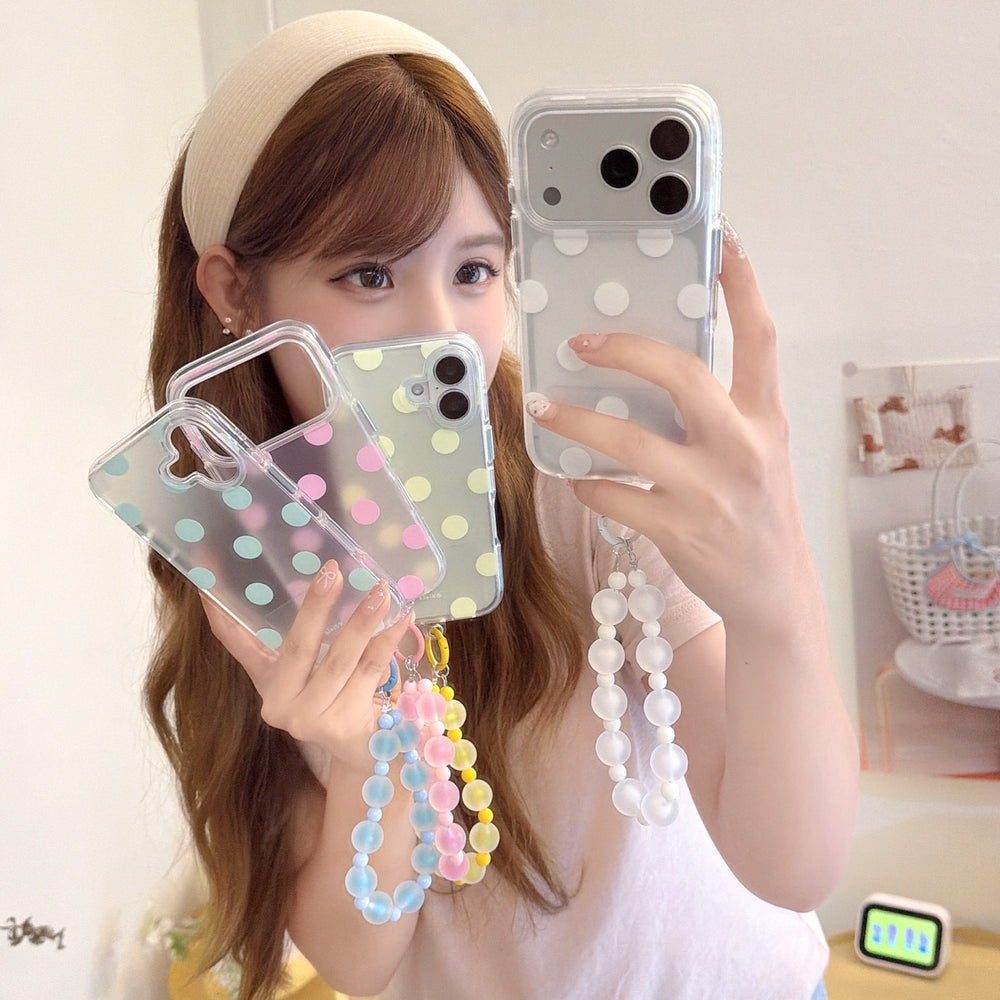 Mirror selfie displaying a white polka dot iPhone case with a clear frosted beaded hand strap.
