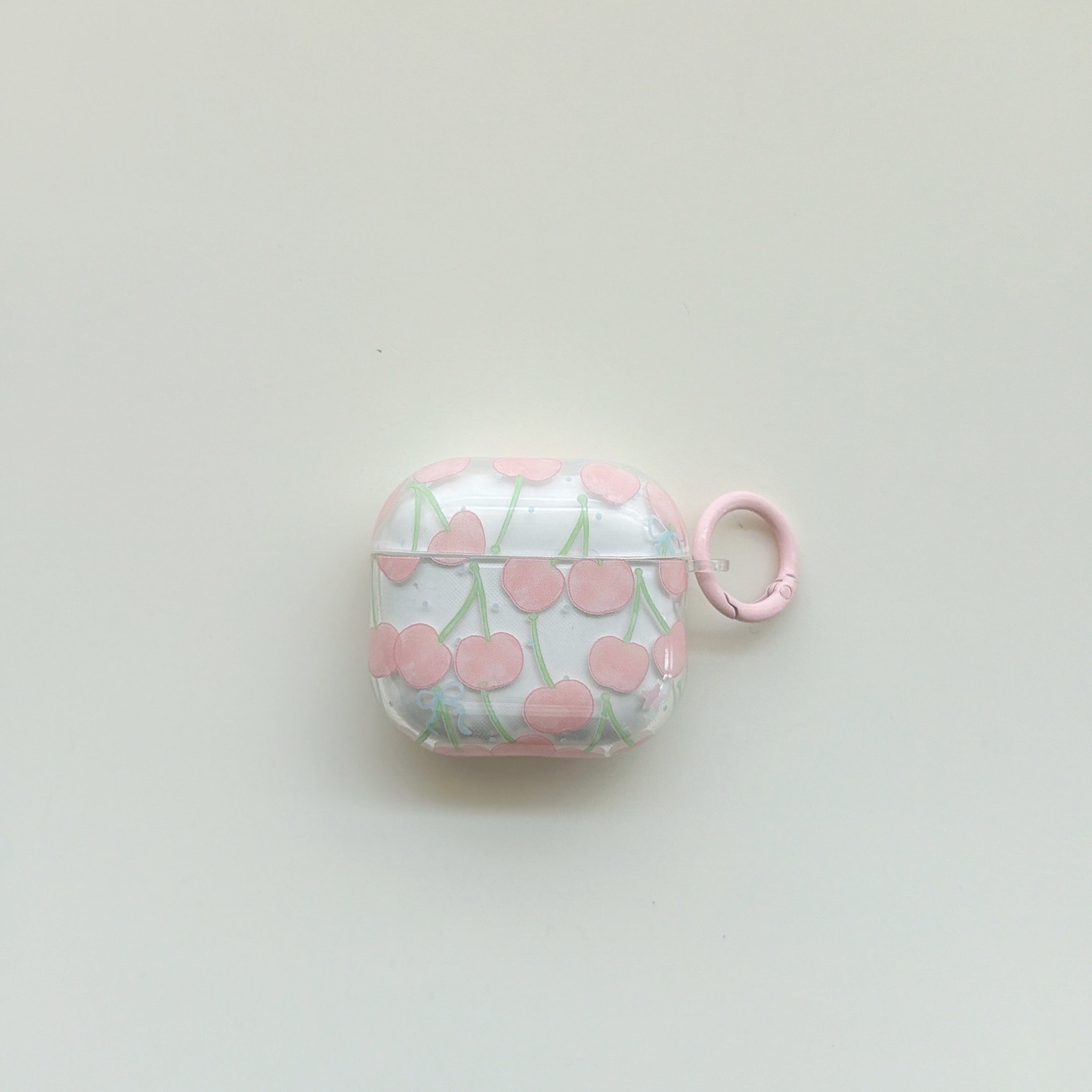 A front centered view of a cute clear AirPods case with a pink cherry pattern and a matching pink ring.
