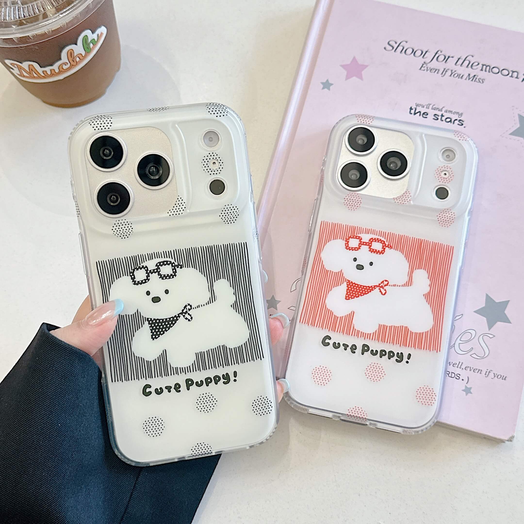 Black and red puppy iPhone cases displayed beside a pink book.