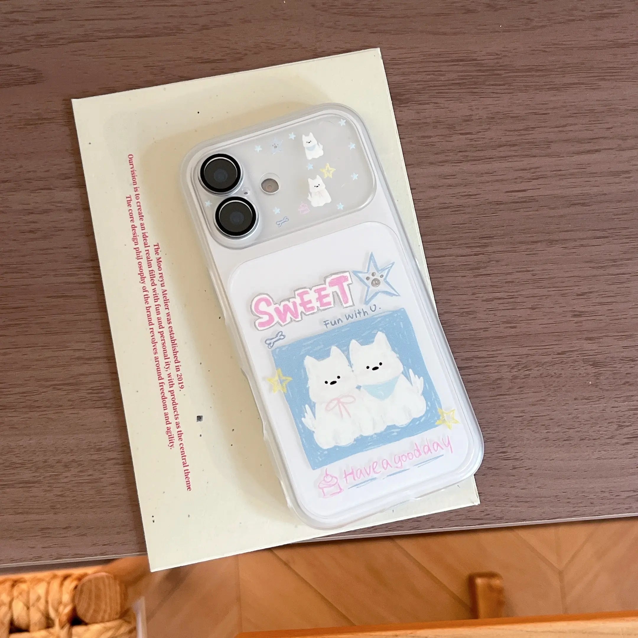 An aesthetic flat lay of a cute puppy cartoon iPhone case resting on a vintage cream postcard.
