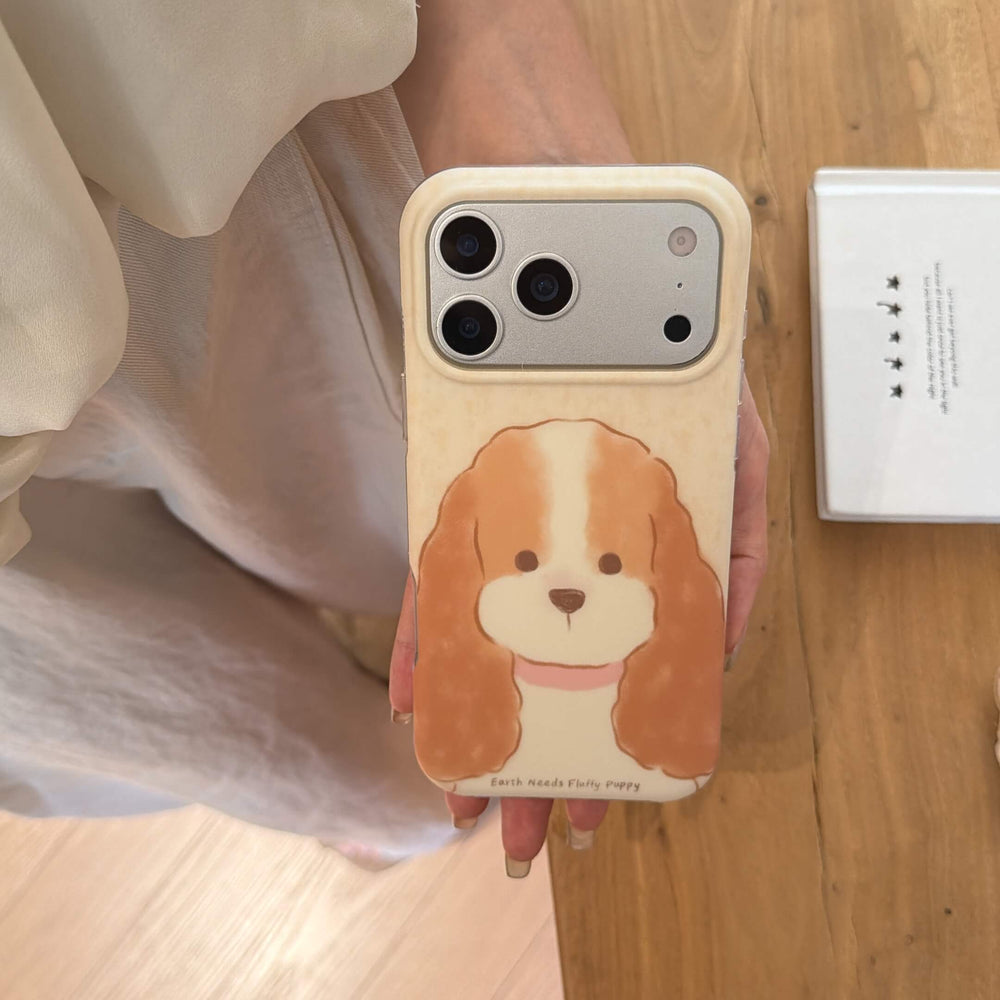Top view of a fluffy puppy iPhone case held over a wooden floor.