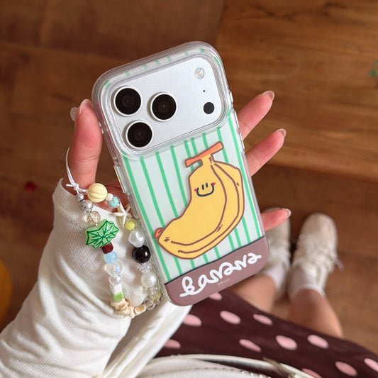 Top view of a hand holding a cute green striped banana phone cover with a colorful beaded charm strap.