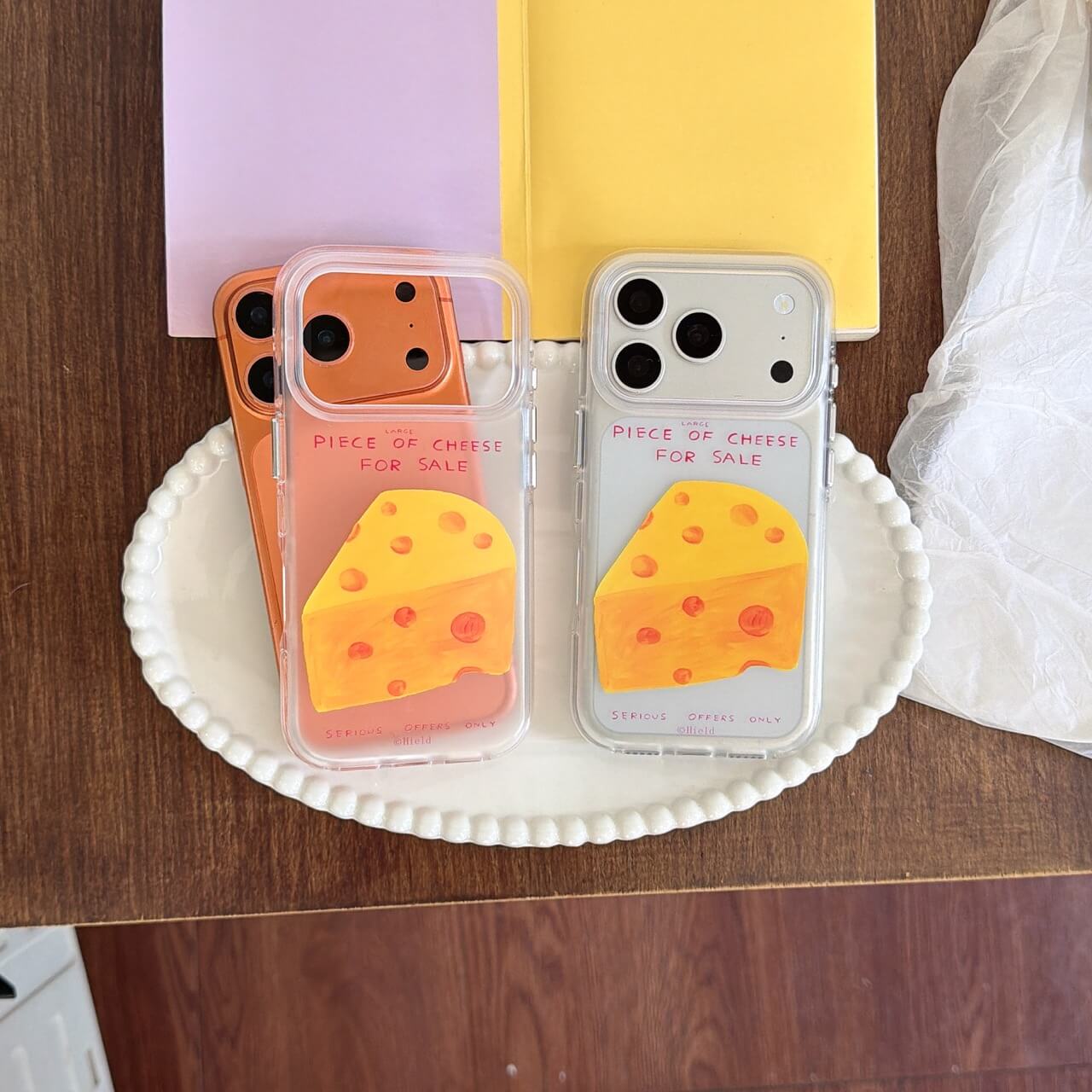 Two funny cheese clear iPhone cases on white tray