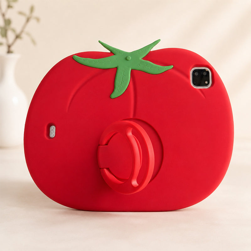 Clean studio display of a funny food design ipad cover shaped like a giant red tomato, standing upright on a minimalist white surface with a blurred white decorative vase in the background.