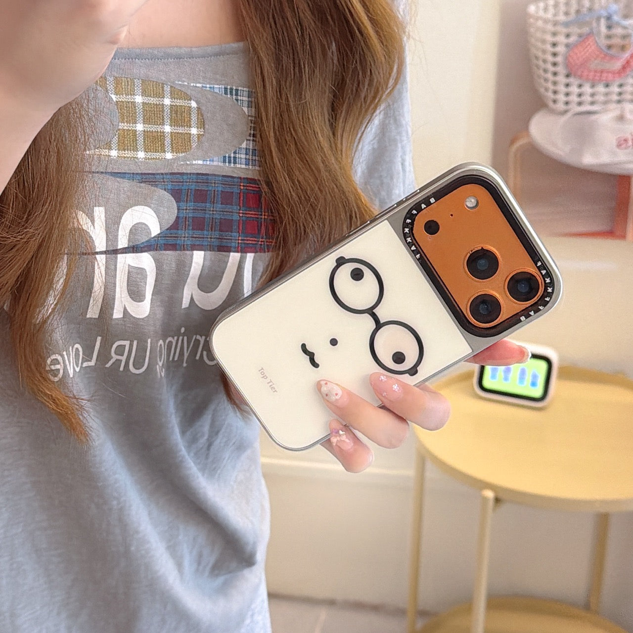 A girl holding a funny nerd glasses iPhone case with a vibrant orange camera base.