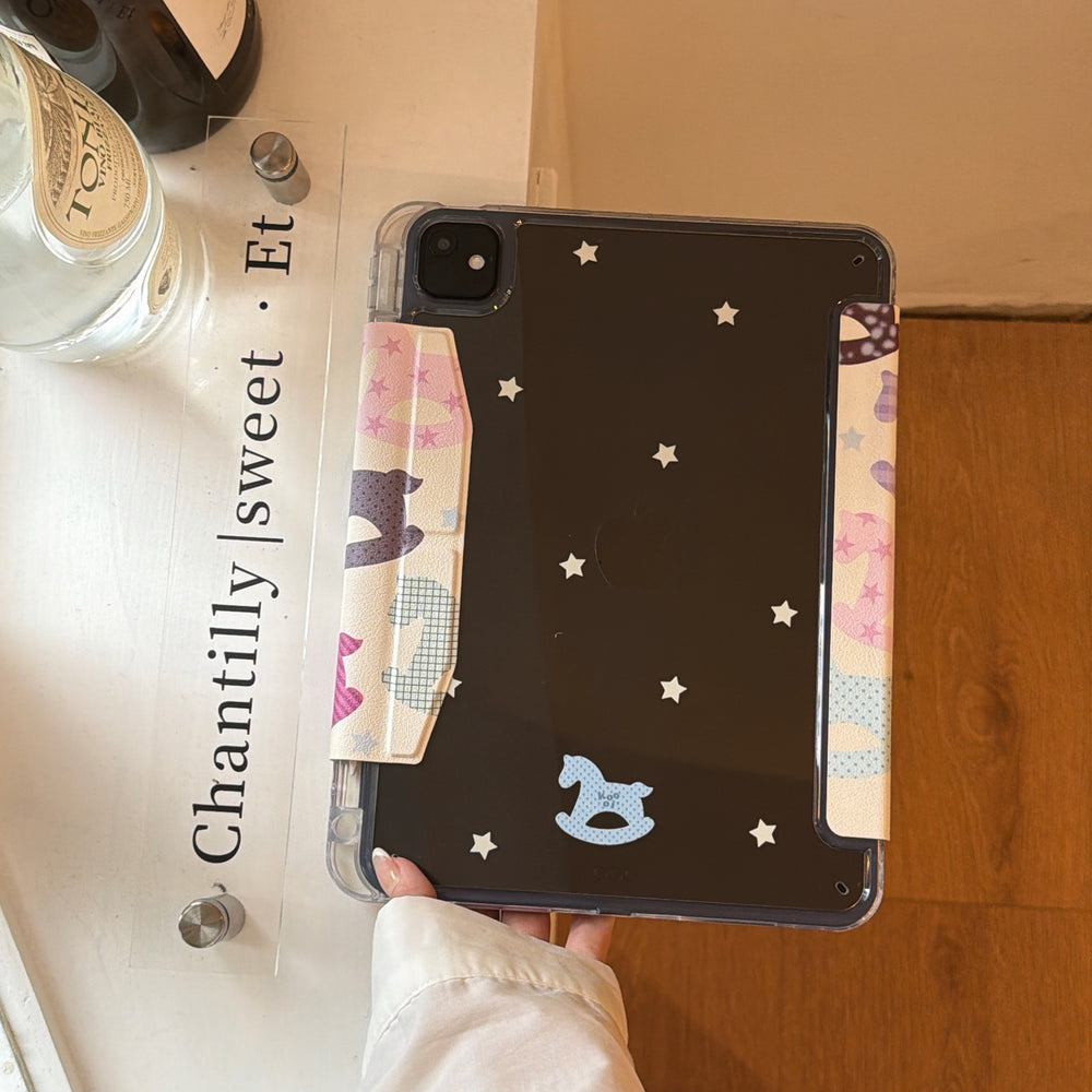 The star-patterned clear back shell of a girly aesthetic pastel pink ipad case resting on a white counter next to a decorative glass sign.