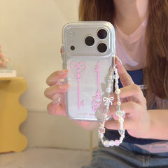 Close-up of a hand holding a clear glittery magic key phone cover featuring a pastel beaded lanyard with a white bow.
