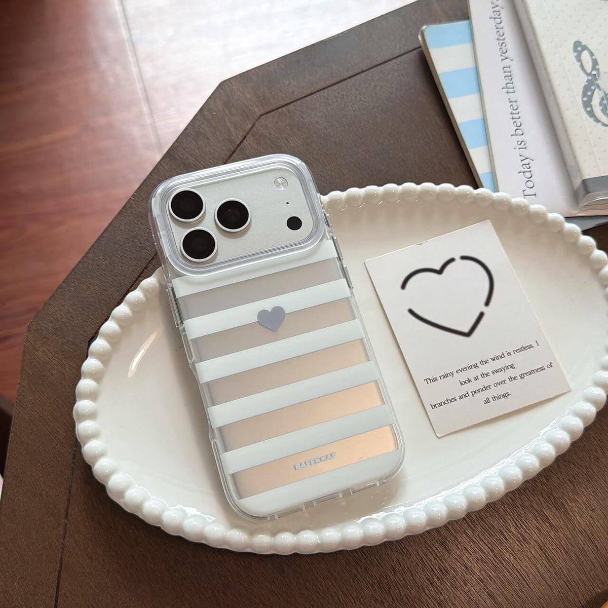Gray stripe clear iPhone case with heart detail on white tray