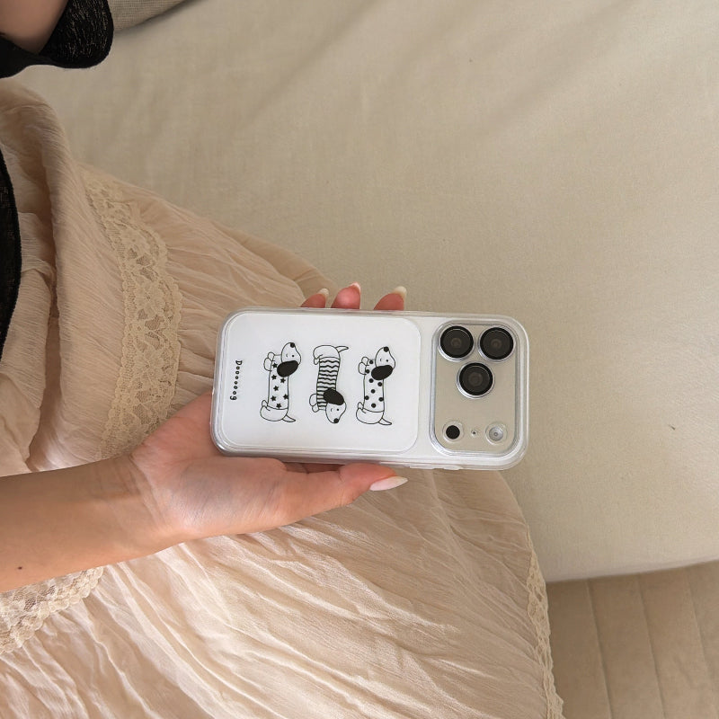 A person holding a clear cartoon wiener dog iPhone case horizontally over a cream lace dress.