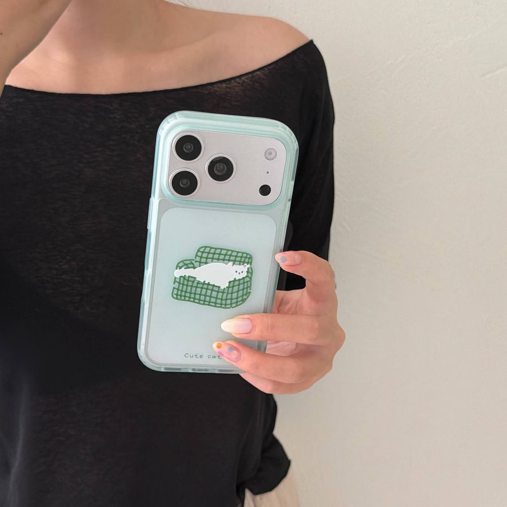 A hand holding a clear mint green lazy cat pattern iPhone case vertically against a plain wall.